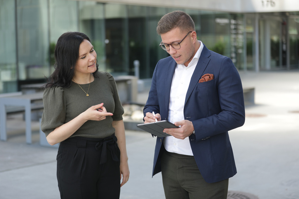I bildet står Inger og Simen og leser stillingsutlysningen om “Frontend Utvikler” i boligbransjen, på et nettbrett.