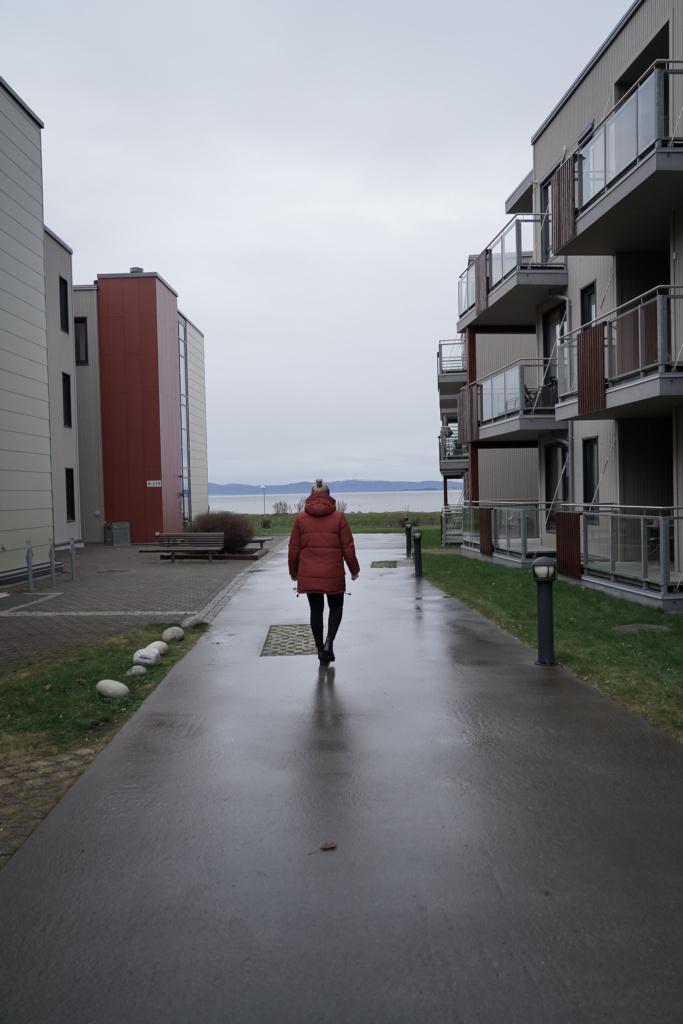 Person går mot fjorden mellom to leilighetsbygninger på Hommelvik Sjøside
