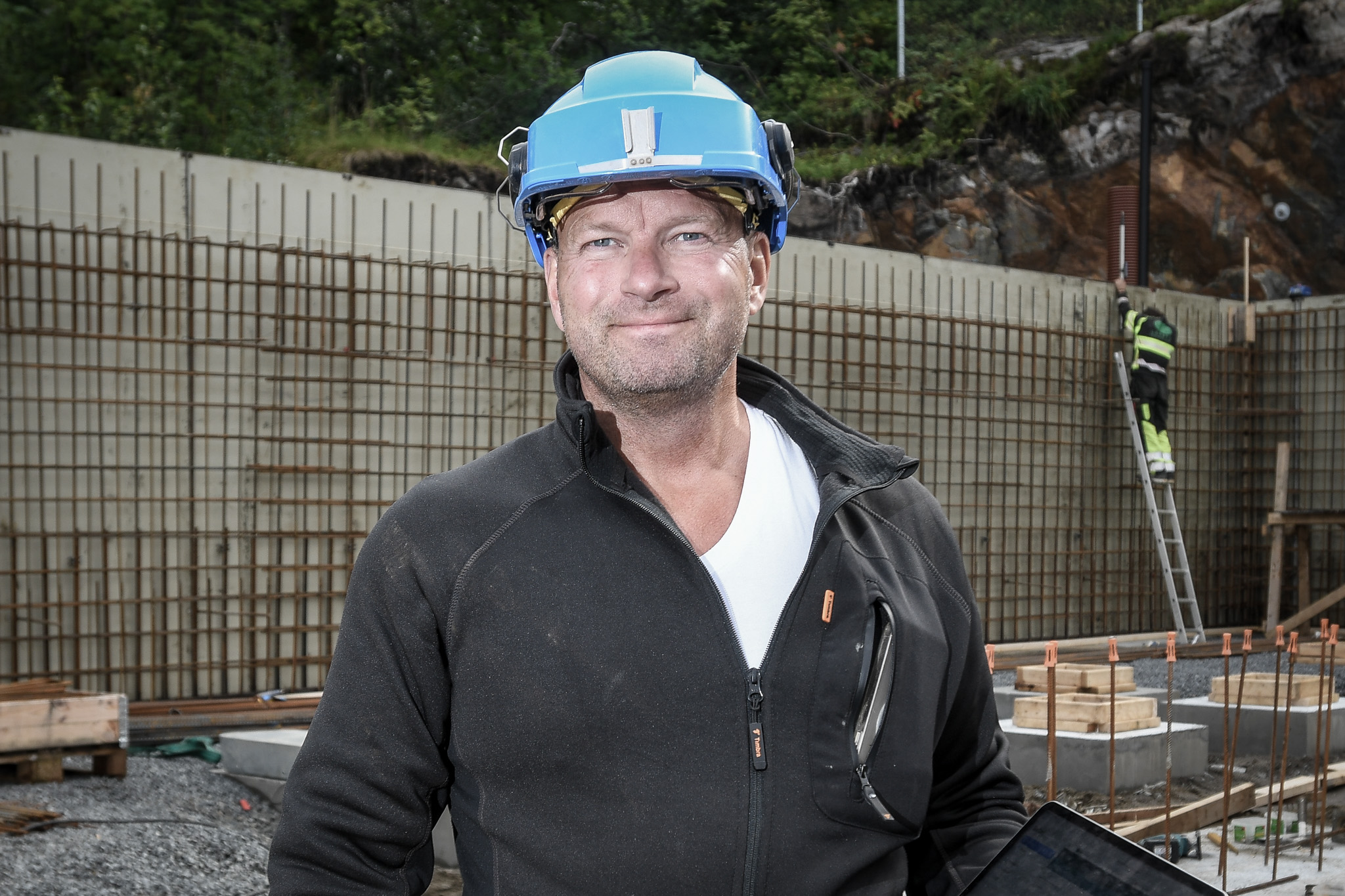 Raymond Bårdsen, medeier i Bolig for Folket, står på en byggeplass med APEX på nettbrettet